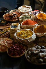 Colorful selection of dried herbs, spices, and natural ingredients in paper bags on rustic market...