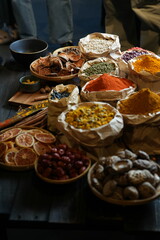 Colorful selection of dried herbs, spices, and natural ingredients in paper bags on rustic market table. Traditional Asian and herbal medicine concept.