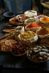 Colorful selection of dried herbs, spices, and natural ingredients in paper bags on rustic market table. Traditional Asian and herbal medicine concept.