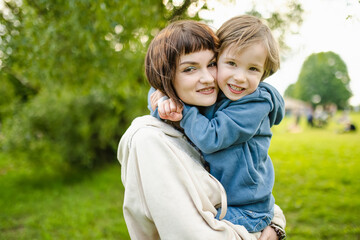Fototapeta premium Cute big sister cuddling with her toddler brother. Adorable teenager girl hugging her small sibling. Children exploring nature.