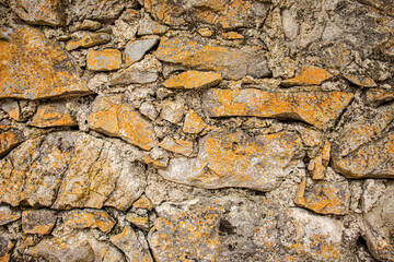 old stone wall with yellow lichen in the Alps