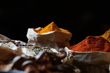 Colorful selection of dried herbs, spices, and natural ingredients in paper bags on rustic market...