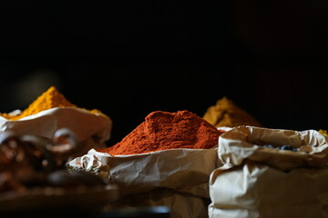 Colorful selection of dried herbs, spices, and natural ingredients in paper bags on rustic market table. Traditional Asian and herbal medicine concept.