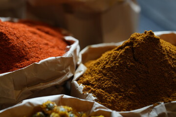 Colorful selection of dried herbs, spices, and natural ingredients in paper bags on rustic market...