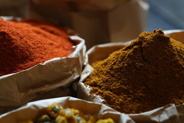 Colorful selection of dried herbs, spices, and natural ingredients in paper bags on rustic market...