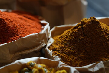 Colorful selection of dried herbs, spices, and natural ingredients in paper bags on rustic market...