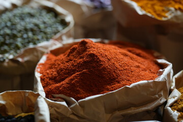 Colorful selection of dried herbs, spices, and natural ingredients in paper bags on rustic market...