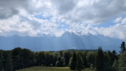 Majestic mountain landscape with dramatic clouds and sun rays over forest valley