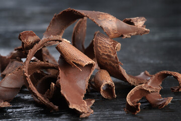 Pieces of dark chocolate on a black wooden background. Close-up