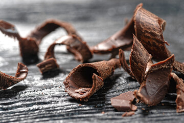 Pieces of dark chocolate on a black wooden background. Close-up