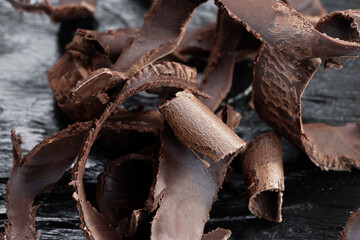 Pieces of dark chocolate on a black wooden background. Close-up