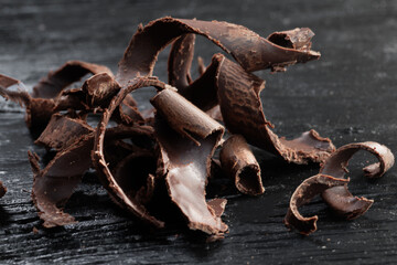 Pieces of dark chocolate on a black wooden background. Close-up