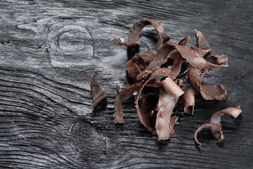 Pieces of dark chocolate on a black wooden background. Close-up