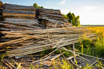 A loosely stacked pile of rough, uneven wood strips and bark-covered slats, wood offcuts or scrap material from milling or carpentry.