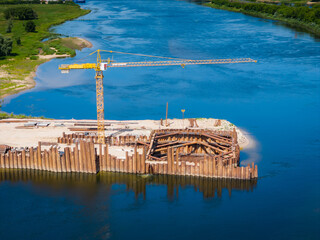 Construction site of new modern bridge construction in Kaunas, Lithuania. Aerial drone view of bridge connecting two shores of a river. Work progress