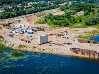 Construction site of new modern bridge construction in Kaunas, Lithuania. Aerial drone view of bridge connecting two shores of a river. Work progress