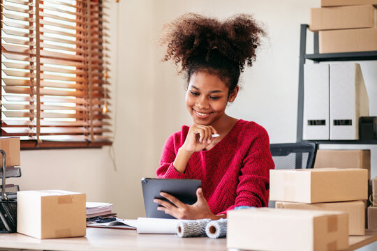 Young African American Woman Running Small Business Online Store Using Tablet for Inventory Management And Online Orders at Home Office