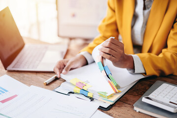 Business Woman Analyzing Financial Data Reports with Laptop Calculator and Hands Sorting Documents...