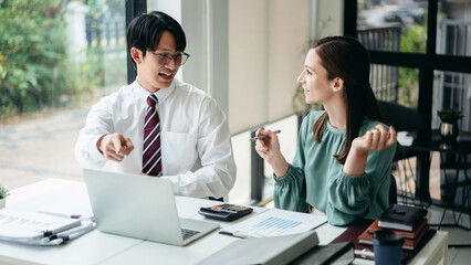 Asian Businessman and Caucasian Businesswoman Collaborating on Laptop in Modern Office for Financial Growth and Business Strategy Planning