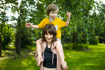 Cute big sister cuddling with her toddler brother. Adorable teenager girl hugging her small sibling. Children exploring nature.
