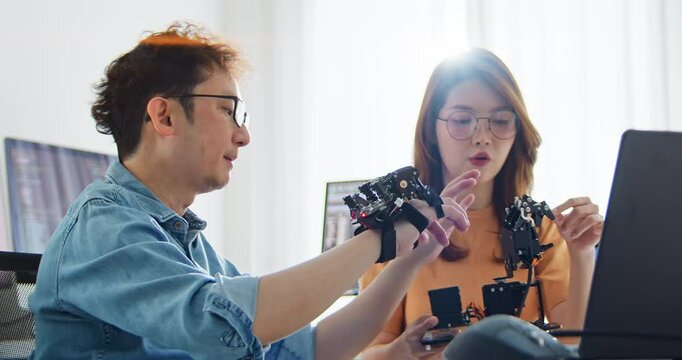 Asian male, female programming developer work together at home office, coding robotic arm machine. Information technology, software engineer programmer job, man woman coworker teamwork concept