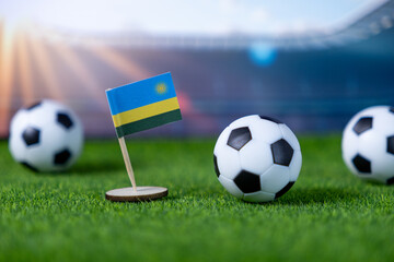 Rwandan flag proudly stands on green turf with soccer balls, symbolizing national football passion and global sports competition inside a stadium