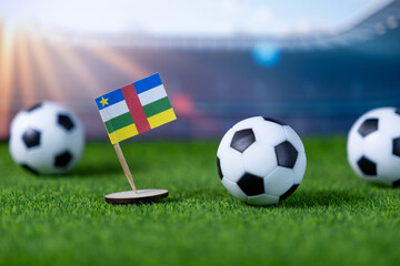 Flag of Central African Republic with soccer balls on green field, symbolizing football, national pride, and international sporting events in a stadium setting