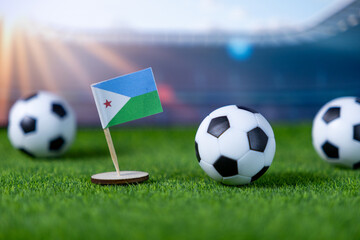 Djibouti national flag and mini soccer balls on green grass, representing international sports events, global football competition, and patriotic team spirit