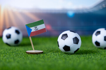 Equatorial Guinea national flag and soccer balls on stadium grass, symbolizing national pride, global competition, and team spirit in sports