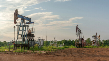 Oil production at the field. Extraction of oil from the reservoir using rocking machines. The construction of the rocking machine. Summer. Beautiful sky and nature