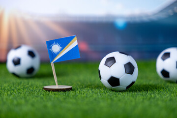 Marshall Islands national flag stands proudly with miniature soccer balls on lush green stadium...