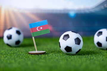 Miniature flag of Azerbaijan stands prominently alongside soccer balls on artificial green grass,...