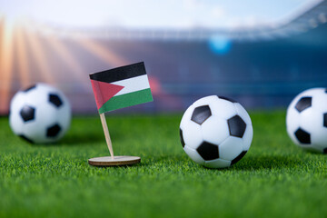 Palestinian flag miniature with soccer balls on green grass, symbolizing national pride and team spirit in an international stadium backdrop