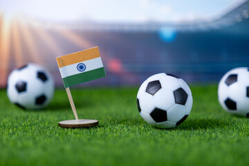 Miniature flag of India with classic soccer balls on a stadium grass field, highlighting national pride and the excitement of international football