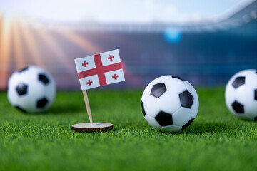 Georgian flag proudly stands with soccer balls on green grass, representing national team, international football championship, and fan enthusiasm in stadium