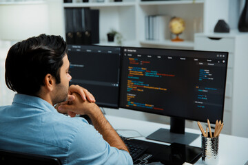 Concentrating in smart IT developer working software development coding on two pc screen, creating...