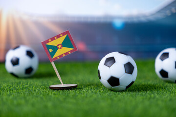 Grenada flag on artificial green grass with soccer balls, depicting the national pride and passion...
