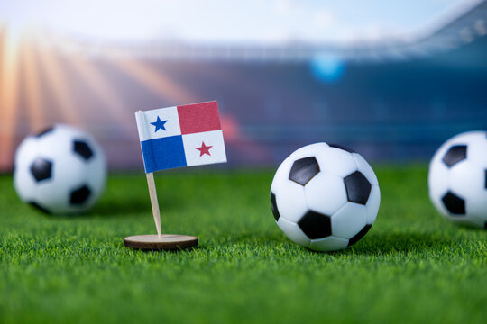 Small Panamanian flag and soccer balls on green turf, representing national team pride and international football competition in a stadium, with ample copy space - Powered by Adobe