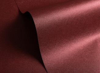 Designer paper closeup. Minimalistic red and marsala surface with pearlescent gloss, wavy folds,