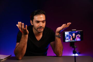 Broadcaster talking to listener on live streaming online with blurred smartphone screen while...