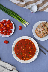 tomato soup with sweet corn and green onions on the table