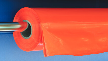 A roll of plastic polyethylene film is cut by a food packaging machine. Industrial concept...
