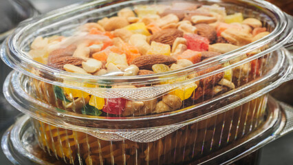 Container of food with nuts and fruit in it. The container is clear and has a lid