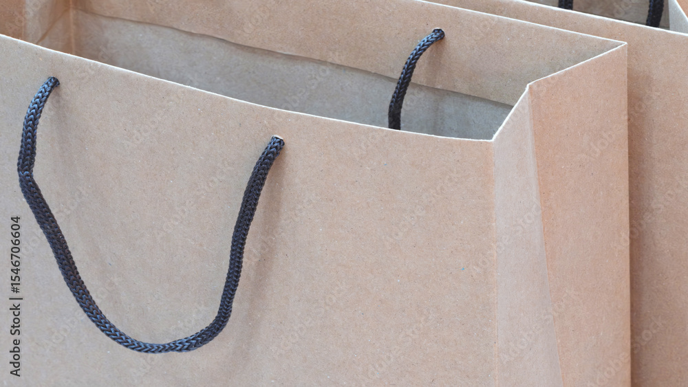 Poster two brown paper bags with black strings. one bag is on the left and the other is on the right