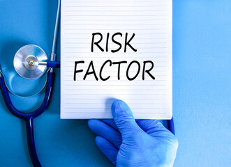 Risk factor symbol. Concept words Risk factor on beautiful white note. Doctor's hand in blue...