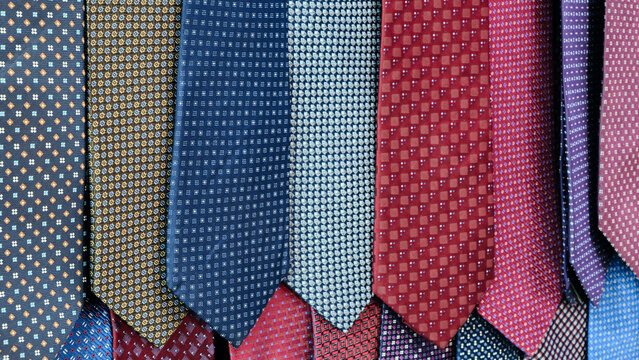 Row of ties with different patterns and colors. ties are hanging on a wall. Concept of variety and choice, as different patterns