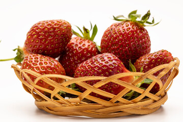 A basket filled with fresh, ripe strawberries. The strawberries are bright red with green leaves,...