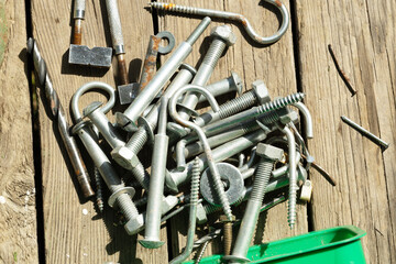 A collection of various metal fasteners including bolts, screws, and hooks scattered on a wooden...