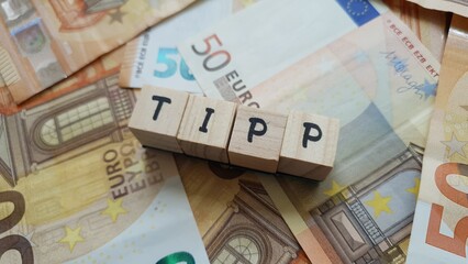 TIPP acronym made of wooden letter cubes on pile of Euro banknotes. Taxe Intérieure sur les...