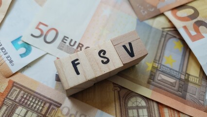 FSV acronym made of wooden letter cubes on pile of Euro banknotes. Fonds de Solidarité Vieillesse...